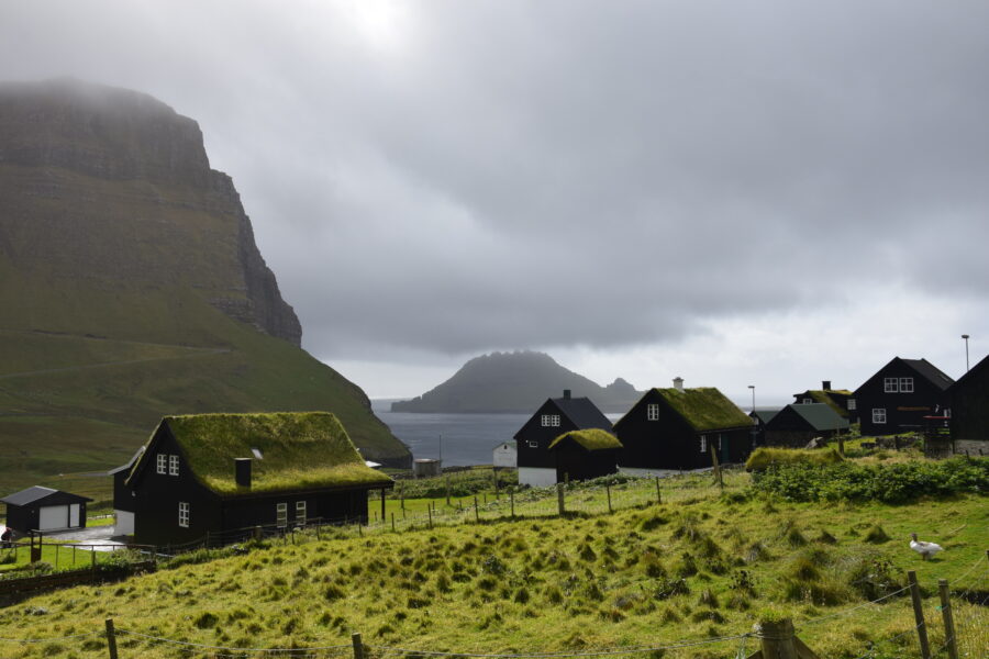 Scenic view of Gásadalur village in the Faroe Islands, featuring dramatic cliffs and a waterfall cascading into the ocean.