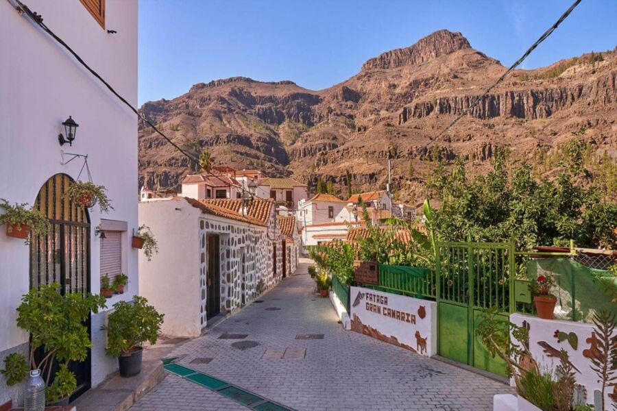 Charming village street with white houses, terracotta roofs, and mountain backdrop in Gran Canaria.
