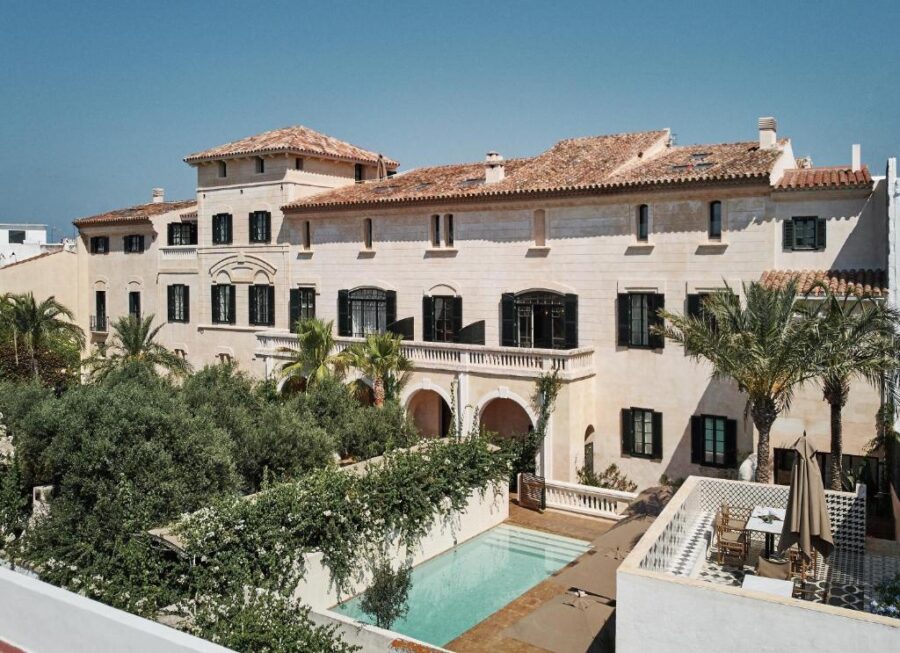 The Faustino Gran Relais & Chateaux features a spacious white house, a pool, and lush palm trees in the landscape.