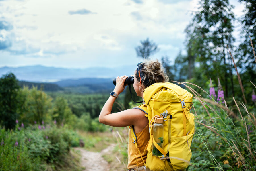 Female backpacker hiking through nature, equipped with a backpack, enjoying the great outdoors