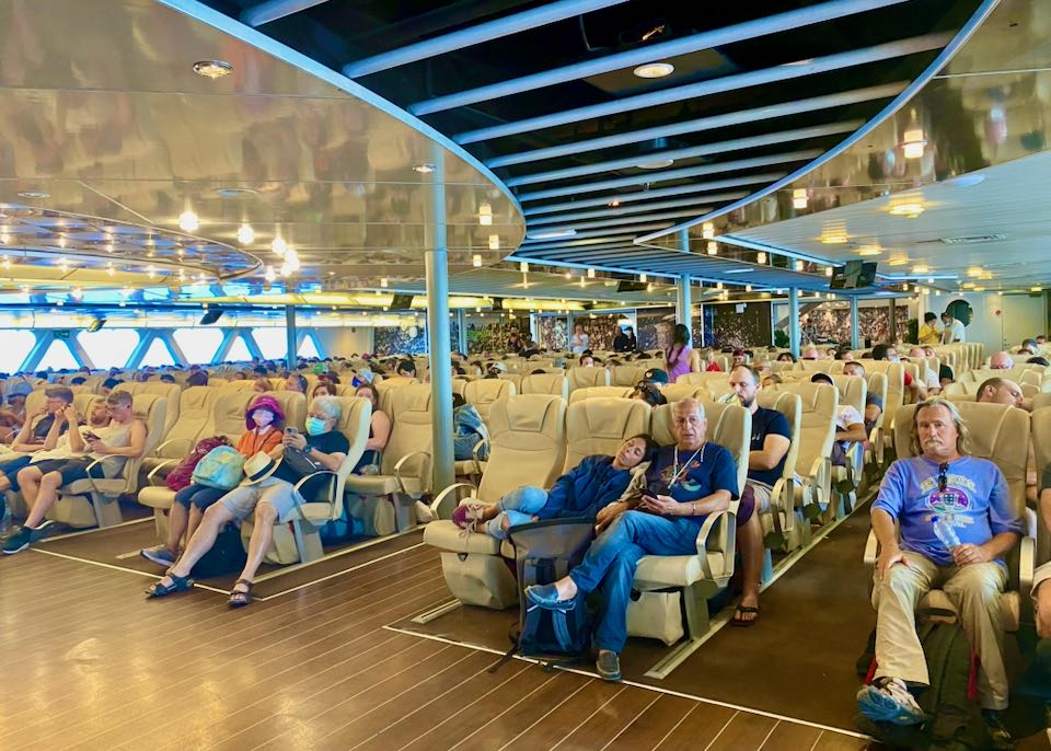 Passenger seating on ferry with diverse travelers, bright lighting, and health protocols.