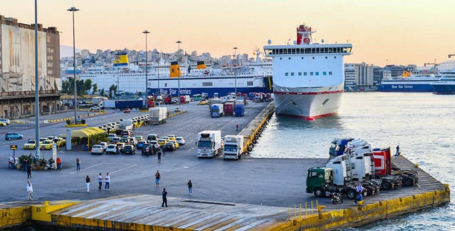 Bustling port scene with ferries, trucks, taxis, passengers at sunset in Piraeus.