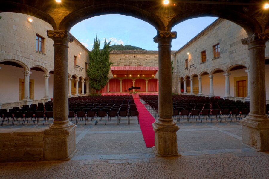 Rows of empty seats arranged in a picturesque outdoor setting at the Festival de Pollença, surrounded by greenery