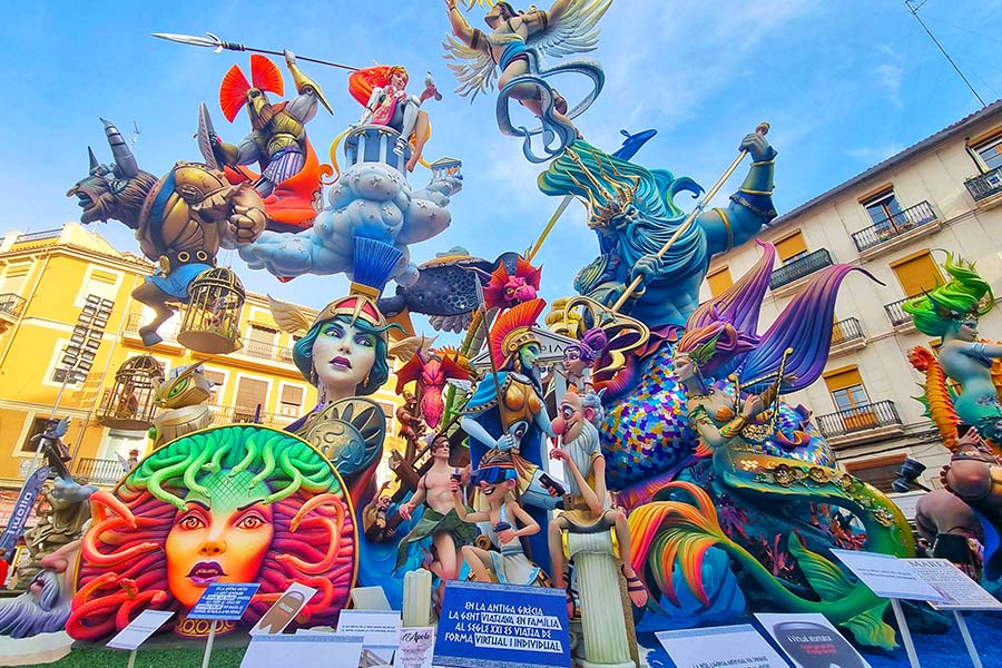 Vibrant sculptures of mythological beings in a festive Las Fallas celebration under a blue sky.