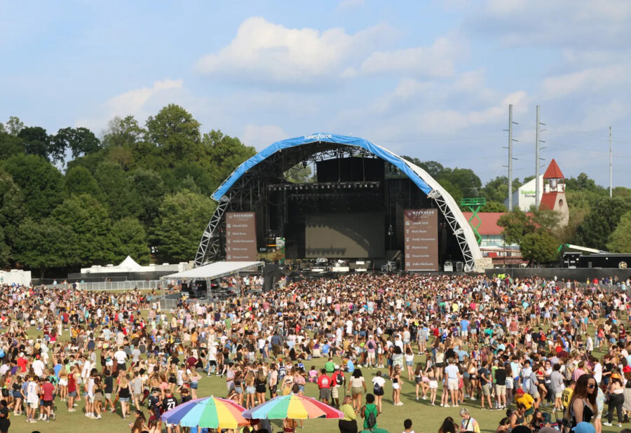 Outdoor music festival in Atlanta with vibrant crowd and stage under blue canopy.