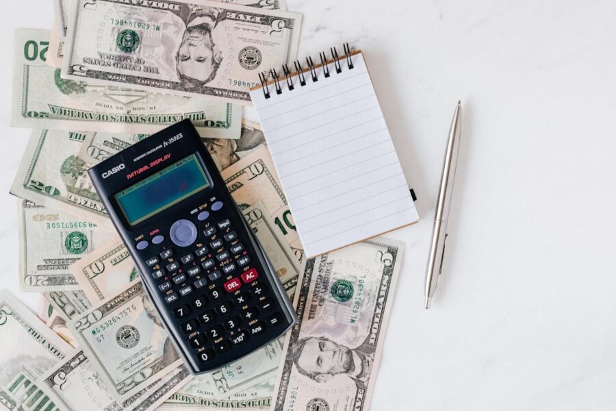 Financial planning with calculator, cash, notepad, and pen for budgeting and calculations.