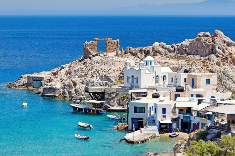 Scenic view of Firopotamos beach in Milos, Greece, featuring colorful fishing boats and clear blue waters
