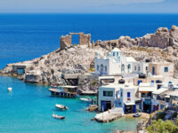 Coastal village of Firopotamos, Milos, featuring a blue-domed church, white houses, and rocky cliffs by the clear sea.