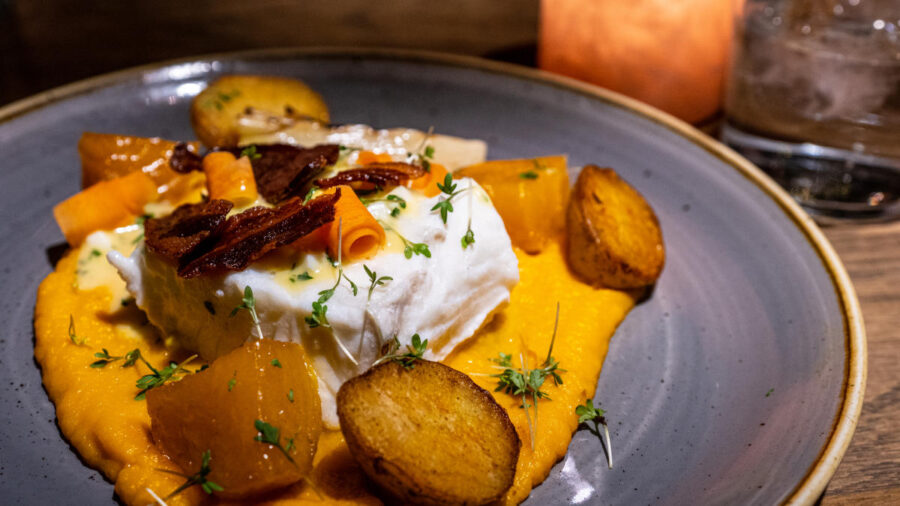 Beautifully plated fish dish with vibrant vegetables and rich puree.