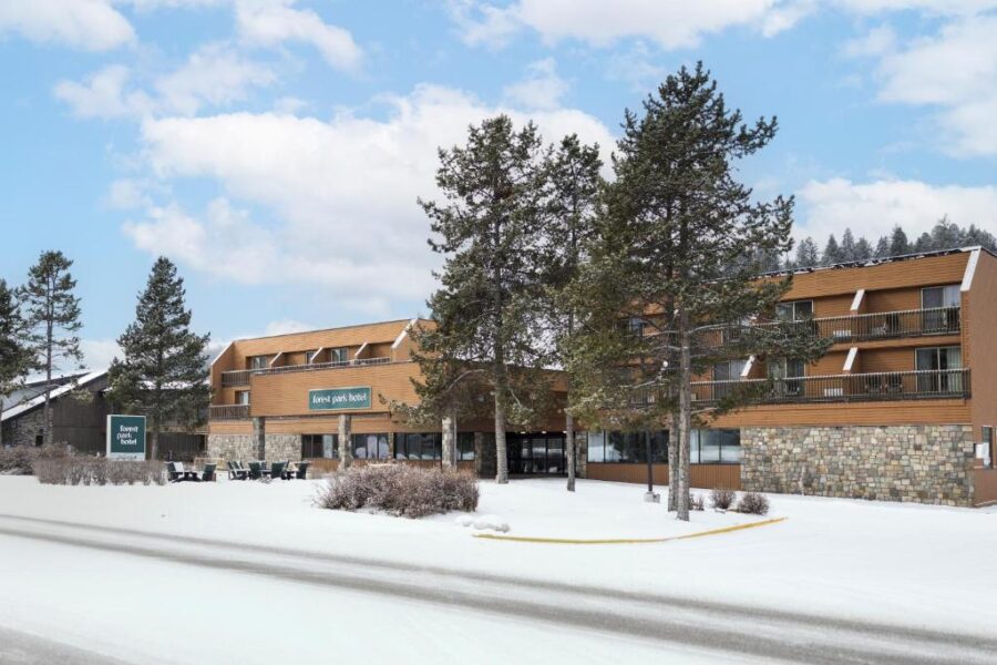 The Forest Park Hotel in Jasper, Canada, surrounded by snow, highlighting its winter charm and inviting entrance.