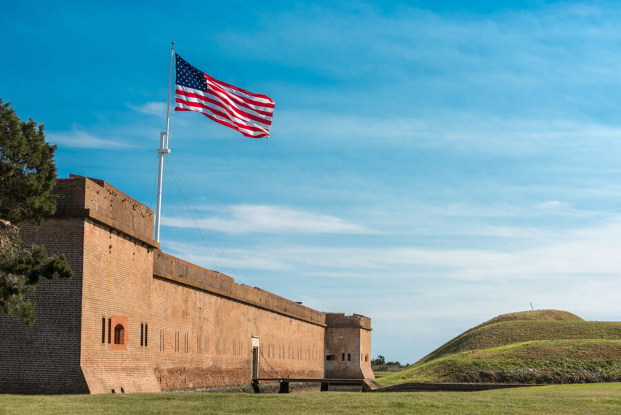 Fort Pulaski National Monument with an American flag waving in the foreground against a clear blue sky