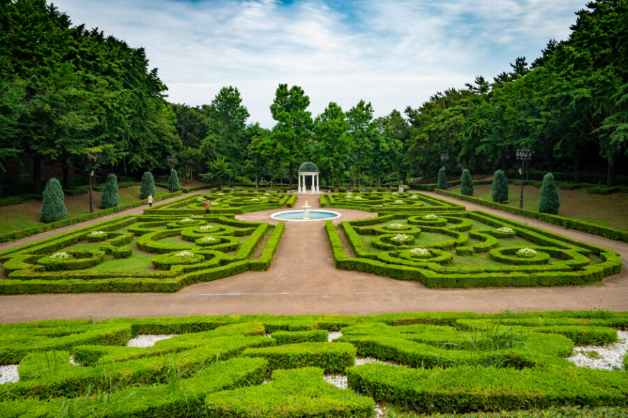 Symmetrical formal parterre garden with central fountain, hedges, pavilion and trees in Jeju Jungmun.