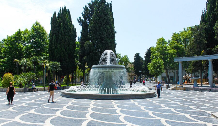 People walking around a fountain in Fountains Square, a lively park scene in Baku, Azerbaijan.