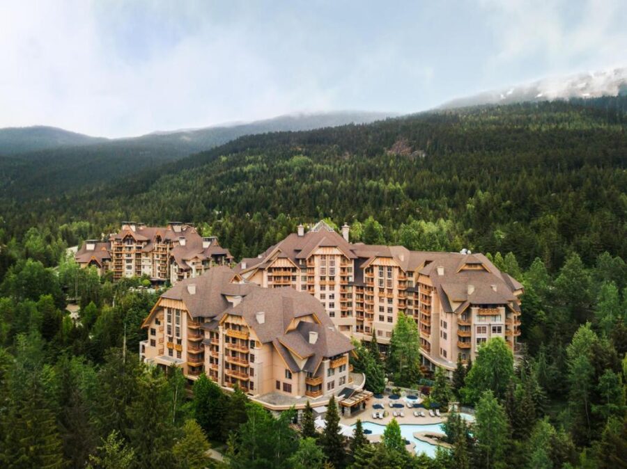 The Four Seasons Resort at Whistler Mountain, showcasing a luxurious lodge surrounded by snow-capped peaks and pine trees.
