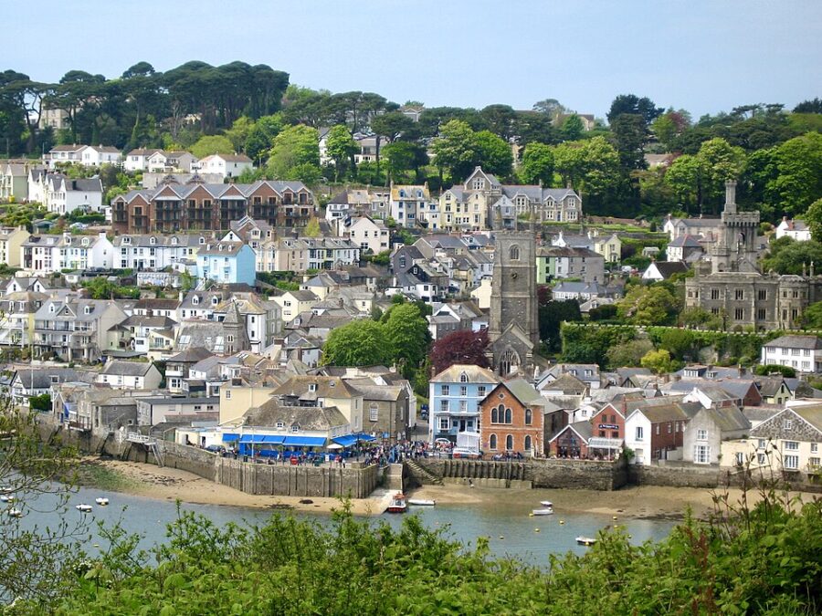Scenic view of Fowey, Cornwall, featuring a river with boats and charming town architecture along the waterfront.