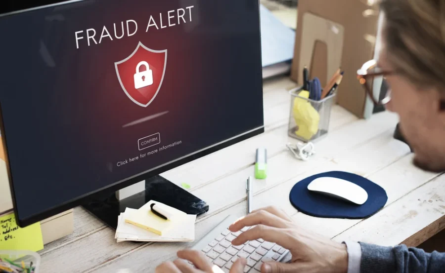 Computer workspace with critical fraud alert warning and security concern.