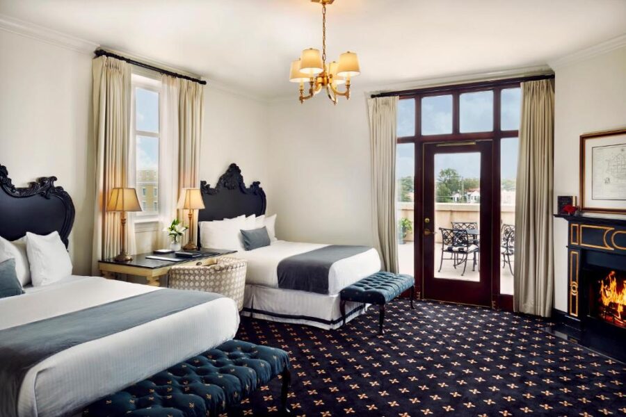 Hotel room at French Quarter Inn features two beds and a cozy fireplace in Charleston, South Carolina.
