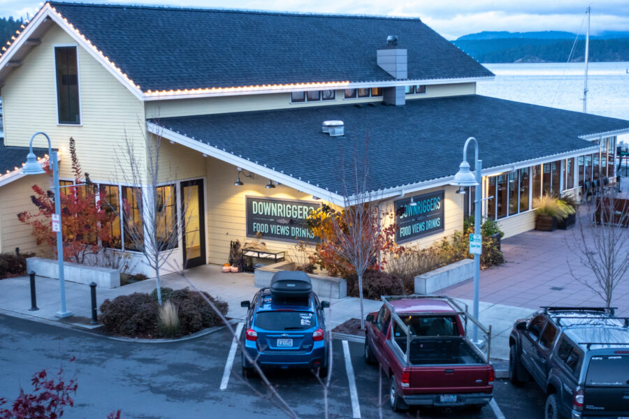 High angle view of Downriggers restaurant in Friday Harbor, WA at dusk, showcasing its illuminated exterior and surrounding scenery.