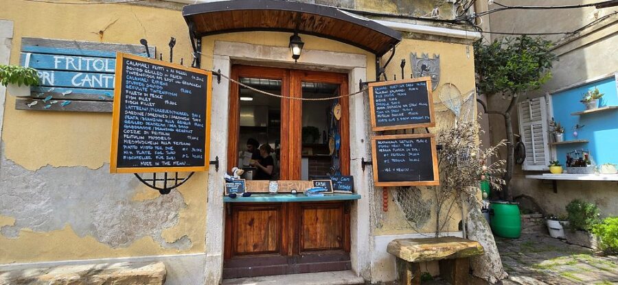 Fritolin Pri Cantini cafe in Piran, Slovenia, showcasing a menu on its door for patrons to view.