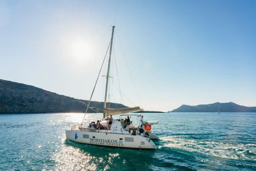 Sailboat with people on board glides through the open ocean during the Santorini Catamaran Sailing Cruise.