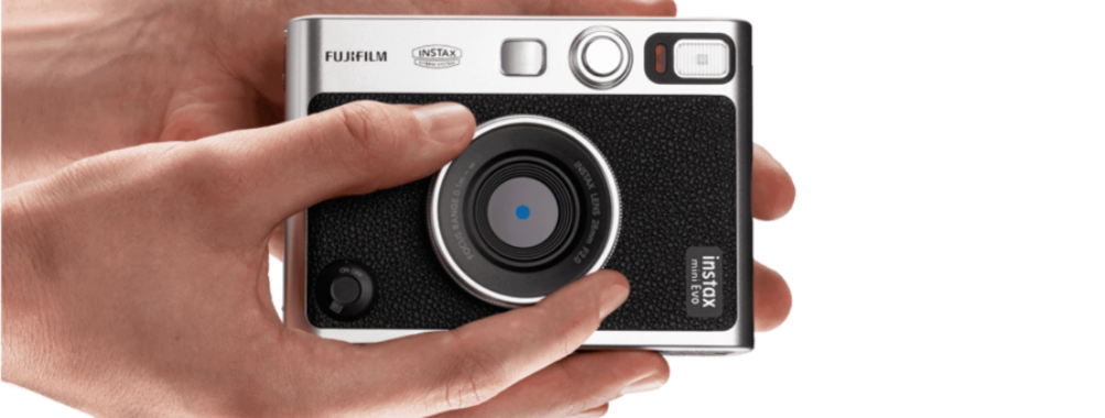 Person holding Fujifilm Instax camera, ready to capture creative instant photo memories.