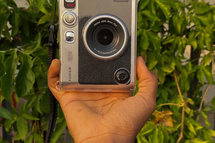 Fujifilm camera held against lush greenery, emphasizing vintage design and outdoor photography.