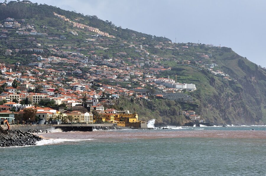 Tranquil waters in Funchal, Madeira Island, Portugal, surrounded by lush greenery and distant hills.
