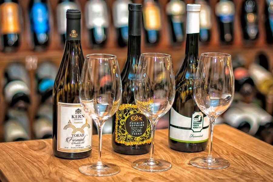 Tokaj Furmint wine bottles and tasting glasses on wooden table.