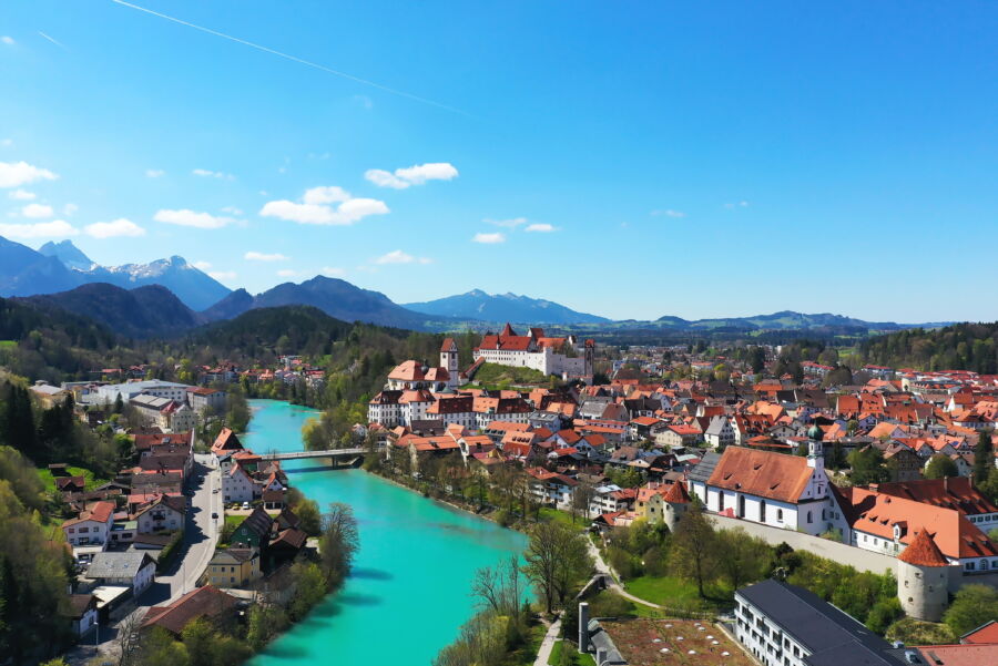 Expansive view of Füssen, Germany, featuring the town's quaint structures against a backdrop of lush hills  