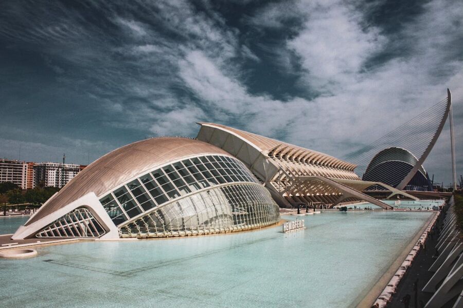 Futuristic architectural structures reflecting on water with curvilinear and jagged designs.