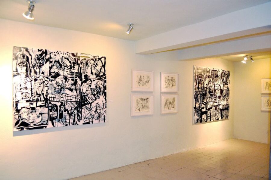 Black and white paintings displayed on a white wall at Galería Nudo, located in San Miguel de Allende.