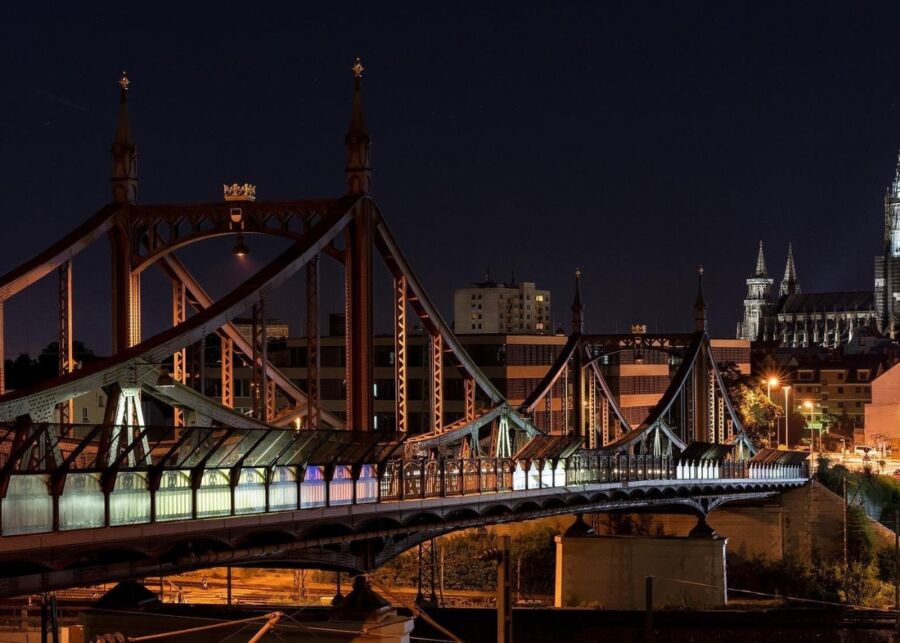 Gänstor Bridge over a river at night, with a cathedral illuminated in the background during a private walking tour in Ulm.
