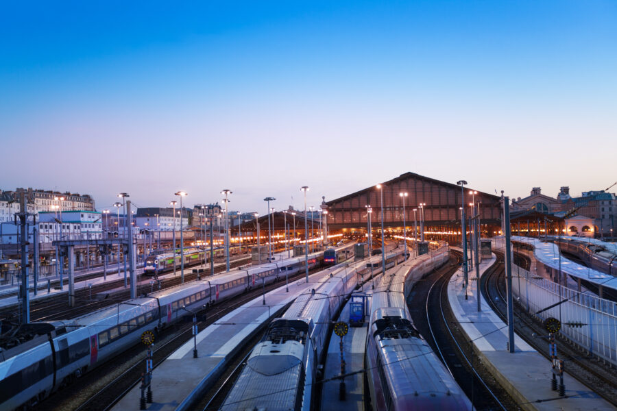 Aerial view of Gare du Nord station illuminated at night, showcasing its architectural beauty and bustling surroundings.