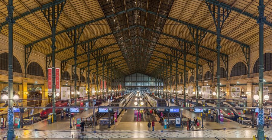 Crowds of travelers moving through Gare du Nord, a bustling train station with various platforms and amenities.