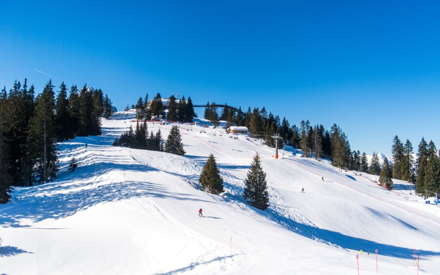 Snowy ski slopes in Garmisch-Partenkirchen, featuring skiers and snowboarders enjoying the winter landscape
