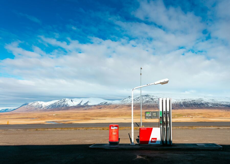 Isolated gas station with mountains, vast field, and dramatic sky in serene landscape.