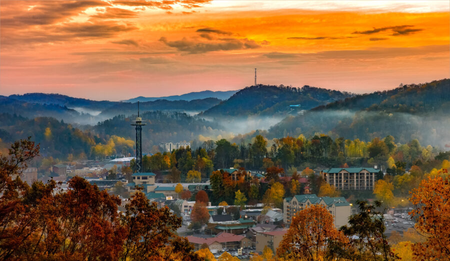 Sunset over Gatlinburg, Tennessee, casting warm hues across the skyline and mountains in the background.