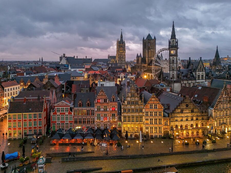 Evening scene of Ghent, Belgium, featuring lit architecture and serene waterways under a twilight sky.