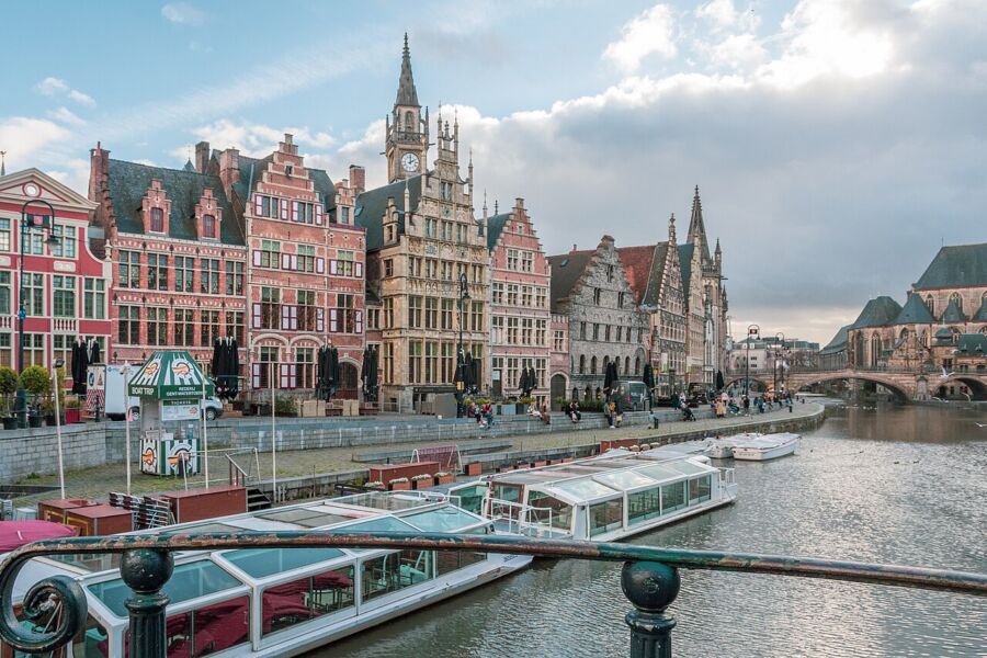 Panoramic view of Ghent, Belgium, featuring a river with boats and historic buildings along the waterfront.
