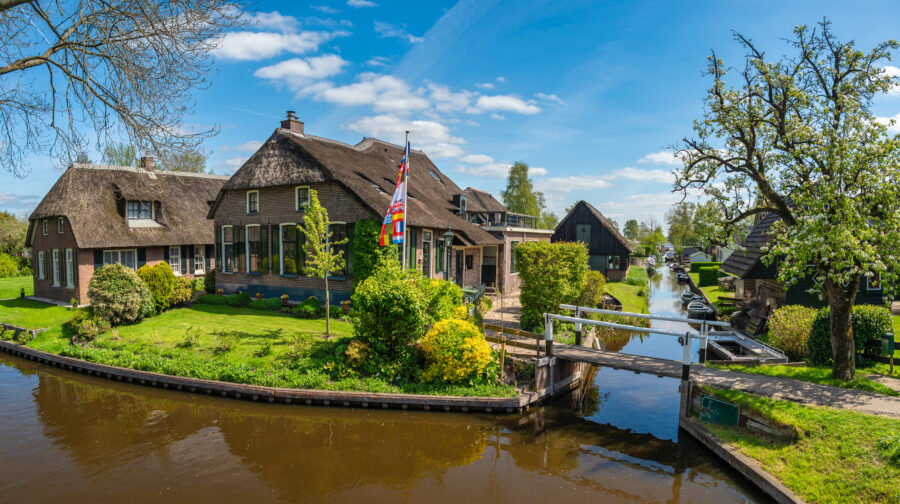 Panorama of Giethoorn, Netherlands, showcasing traditional houses along a serene canal in the picturesque village.
