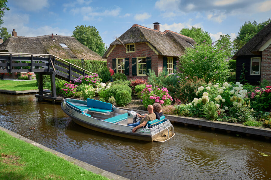 Tourists on a boat in Giethoorn, Netherlands, exploring the charming canals and tranquil landscapes of the village