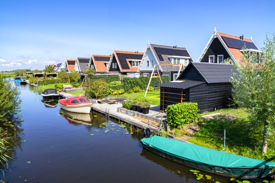 Scenic view of boats on a canal, surrounded by picturesque traditional Dutch houses in Giethoorn, Netherlands.
