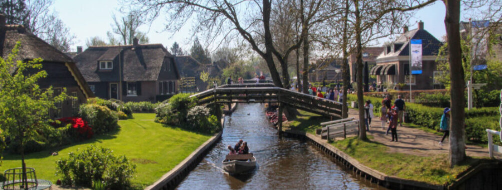 Scenic view of tourists on a boat tour in Giethoorn, Netherlands, navigating through charming canals and quaint houses.