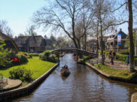 Scenic view of tourists on a boat tour in Giethoorn, Netherlands, navigating through charming canals and quaint houses.