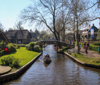 Scenic view of tourists on a boat tour in Giethoorn, Netherlands, navigating through charming canals and quaint houses.