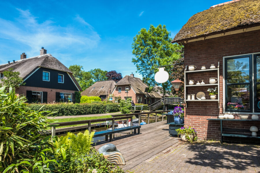 Picturesque scene in Giethoorn, Netherlands, showcasing traditional thatched-roof houses beside serene canals. 