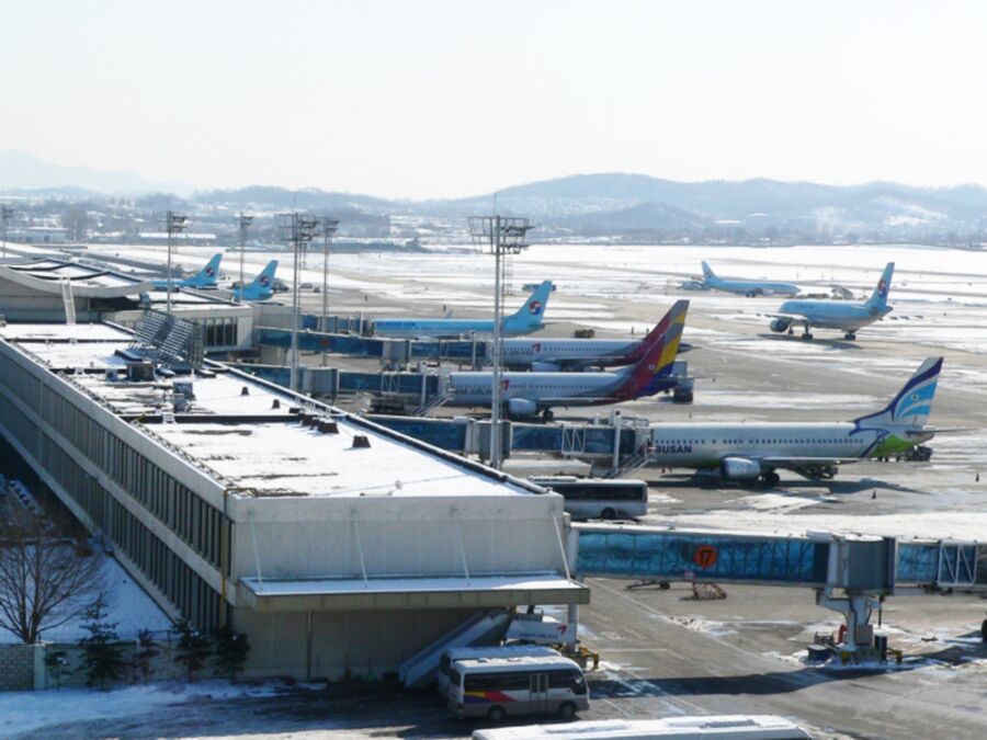 Snow-covered Gimpo International Airport with snowflakes falling, showcasing a winter scene at the terminal.