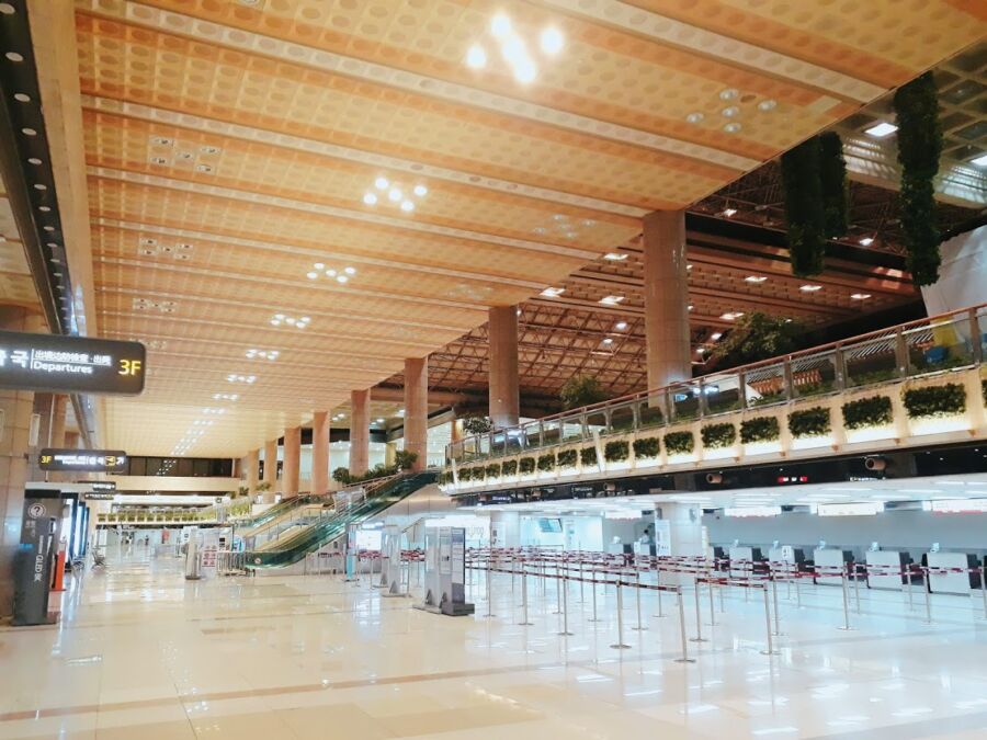 Busy interior of Gimpo International Airport with numerous travelers walking through the terminal.