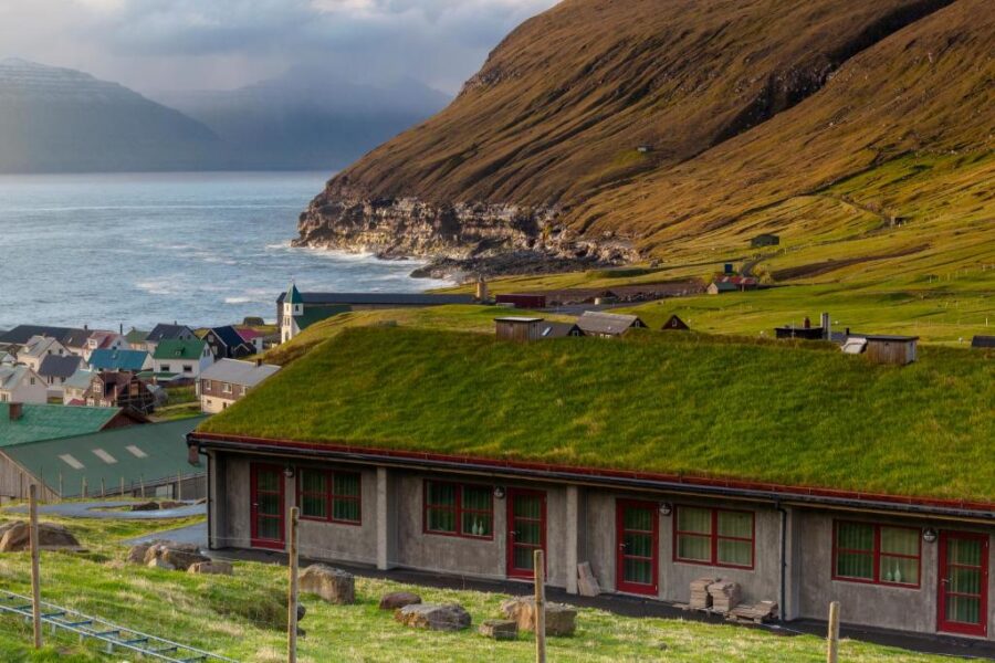 Green roof of Gjaargardur Guesthouse in Gjogv, Faroe Islands, overlooking the rugged Icelandic coastline.