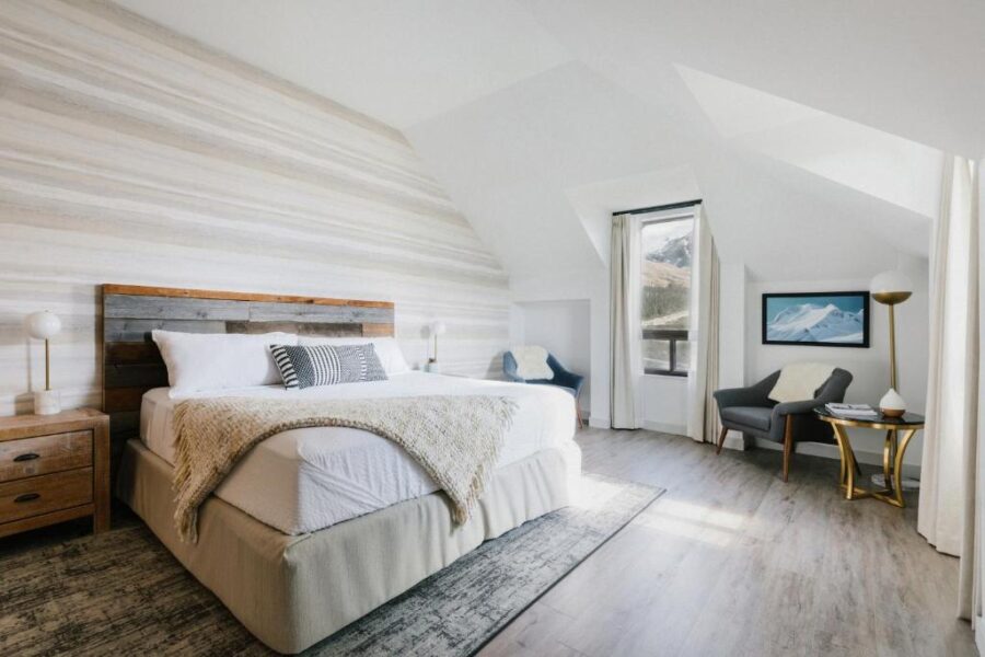Bedroom interior at Glacier View Lodge, showcasing a bed, desk, and chair in a warm, inviting setting.
